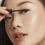 Woman with hooded eyes applying lash adhesive that is made in Korea