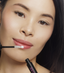Asian woman applying natural looking fake lashes 