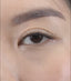 Beautiful woman applying her own lash extensions at home